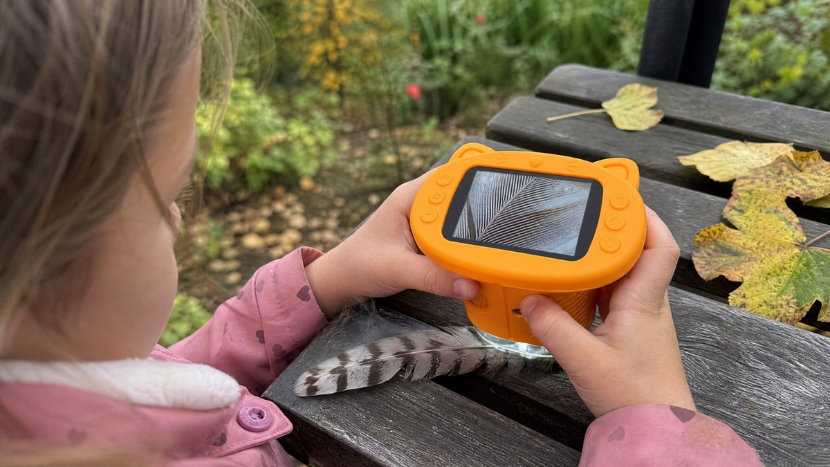 Enfant au jardin qui observe une plume avec le microscope enfant Kideo jaune Image