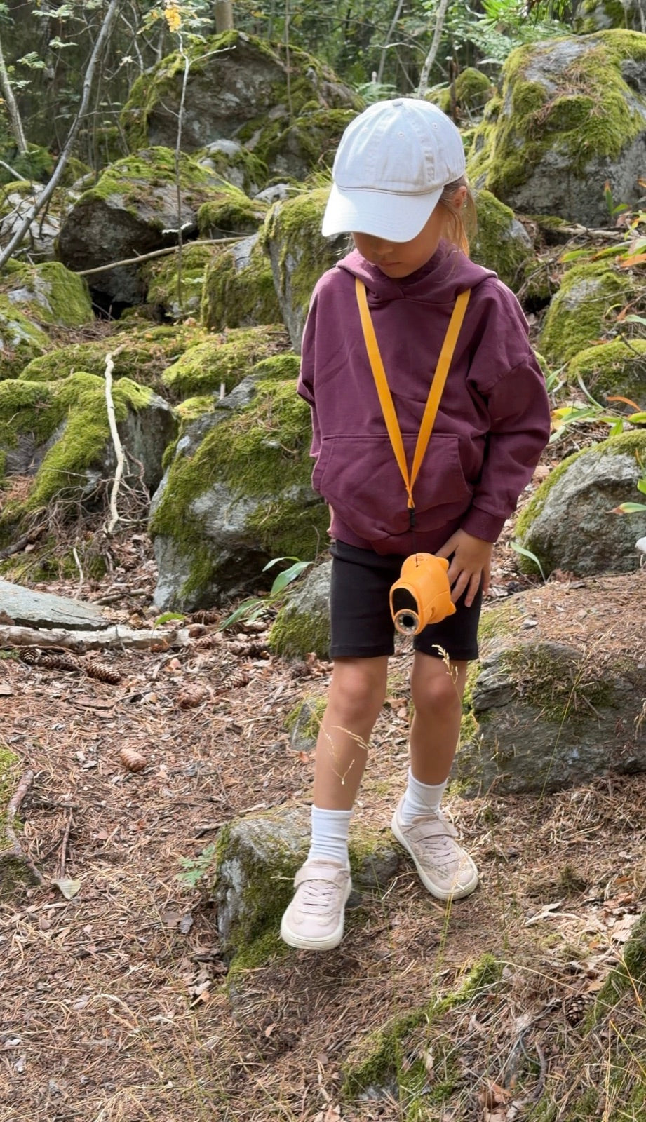 Enfant en balade en forêt avec son microscope de poche Kideo jaune autour du cou Image