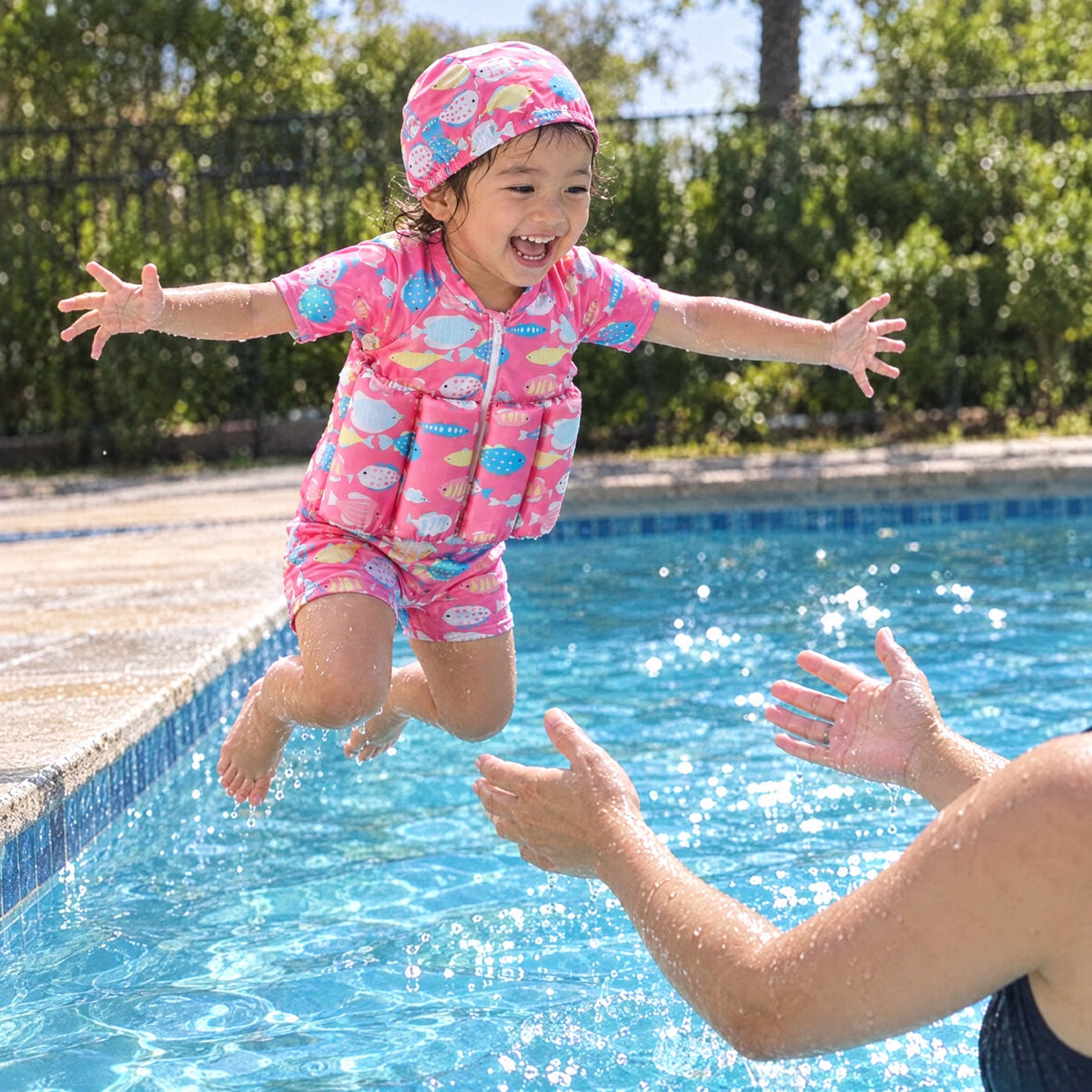 A child jumping into the pool wearing a pink SafePlouf wetsuit